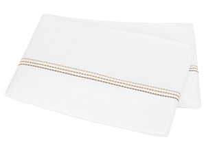 A folded white bedsheet from the Amara Triple Pearl Bedding Collection by Matouk, crafted from luxurious sateen and adorned with an elegant embroidered horizontal stripe of small beige and brown dots near one edge, displayed on a plain background.