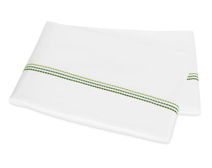 Two folded white pillowcases from the Matouk Amara Triple Pearl Bedding Collection, featuring a green dotted stripe near one edge and an elegant triple pearl embroidered design, placed on a white background.