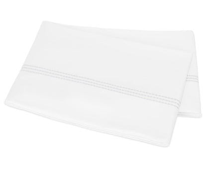 A folded white pillowcase from the Matouk Amara Triple Pearl Bedding Collection, crafted from luxurious sateen and featuring a double line of gray decorative stitching near the edge with an elegant triple pearl embroidered design, is displayed on a plain background.