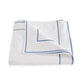 The Ansonia Bedding Collection by Matouk features luxury bedding crafted from premium cotton percale, showcasing a crisp white sheet or blanket adorned with refined blue line borders and delicate satin stitching—an elegant choice for those seeking sophisticated style.