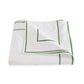 Experience the elegance of luxury bedding with the Ansonia Bedding Collection from Matouk, featuring a folded white cotton percale sheet adorned with a green satin-stitched border and corner design, showcased against a pristine white background.