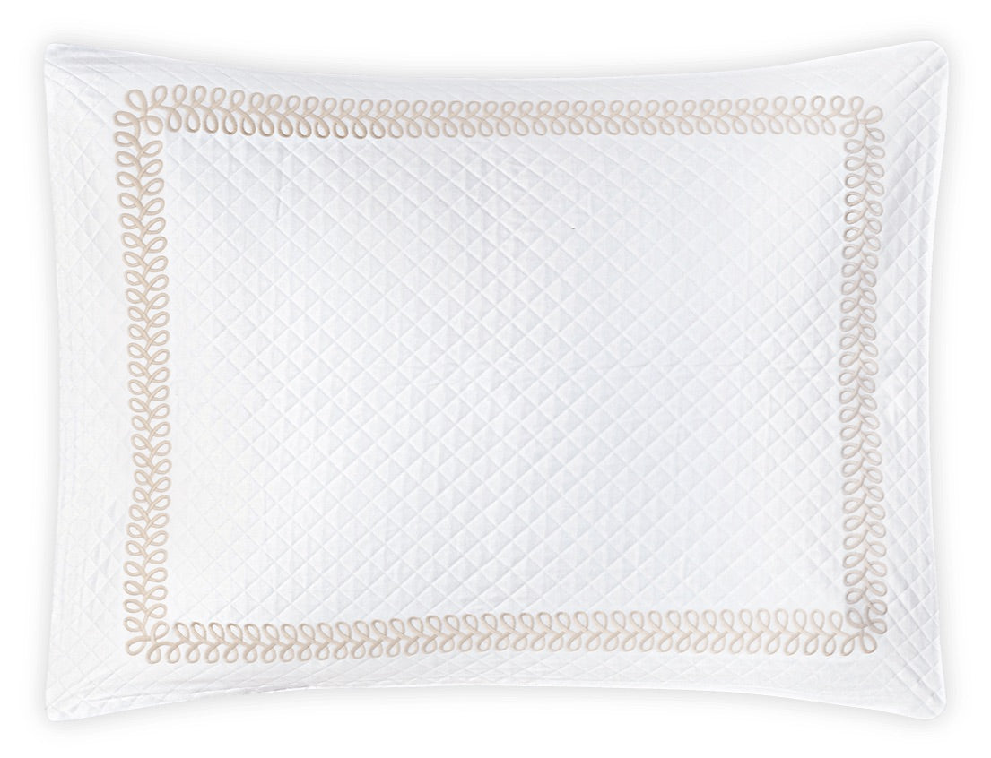 A white quilted pillow sham from the Matouk Astor Braid Matelassé Bedding Collection, featuring a Petra diamond matelassé pattern and a beige looped Astor Braid embroidery border, is photographed from above against a white background for an elegant, Schumacher-inspired look.