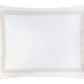 White rectangular pillow featuring a quilted diamond pattern inspired by the Astor Braid Matelassé Bedding Collection, Dune, by Matouk, with a decorative beige braided edge against a black background.