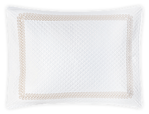 A white quilted pillow from the Matouk Astor Braid Matelassé Bedding Collection, Dune, showcases Astor Braid embroidery with a decorative stitched looping border against a black background.