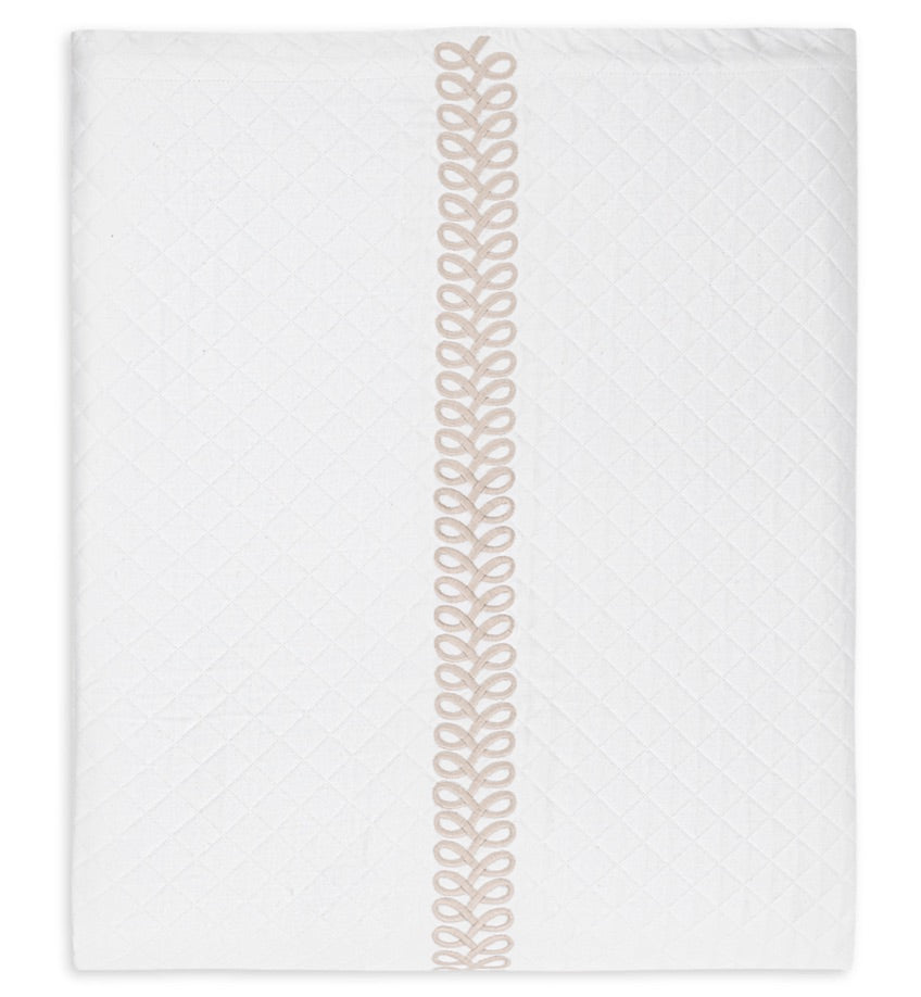 Crafted by Matouk, the Astor Braid Matelassé Bedding Collection features white quilted fabric with a diamond motif inspired by Petra diamond matelassé, accented by a single vertical beige embroidered loop design down the center that evokes classic Astor Braid embroidery.