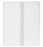A folded white Matouk Astor Braid Matelassé quilt from the Dune collection, featuring a subtle diamond pattern and a vertical beige embroidery loop design in the center.