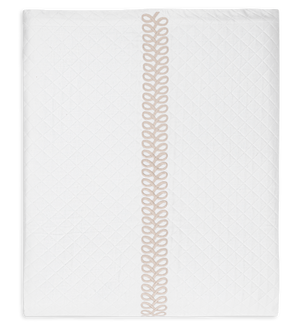 The Matouk Astor Braid Matelassé Bedding Collection in Dune features a white quilt with a Petra diamond matelassé pattern and a beige embroidered central stripe, accented by Astor Braid embroidery.