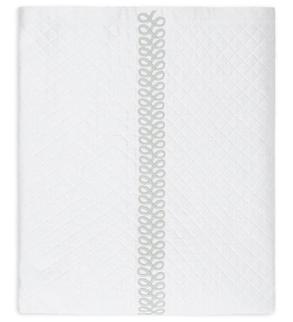 Introducing the Astor Braid Matelassé Bedding Collection by Matouk—a white quilted blanket adorned with a diamond pattern inspired by the Petra diamond matelassé. This refined piece features the signature Astor Braid embroidery as a vertical decorative looped trim down the center, exemplifying elegant craftsmanship from Matouk.