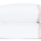 Two white pillows from the Atoll Bedding Collection, Blush by Matouk, made of Ceylon cotton percale with feathery coral embroidery on one end, are stacked against a white background.