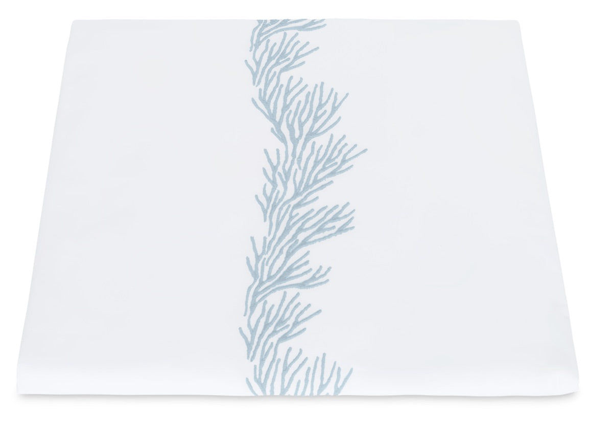 Elevate your table setting with the Atoll Bedding Collection by Matouk, featuring a white tablecloth adorned with a vertical light blue coral embroidery down the center, expertly crafted from luxurious CEYLON cotton percale with a silky-smooth 520 thread count.