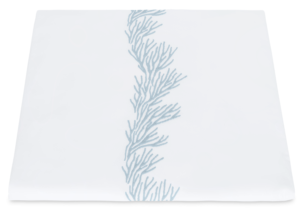 The Atoll Bedding Collection by Matouk for Wedgwood features a white Ceylon cotton percale table runner accented with vertical light blue coral branches and a refined satin stitch border.