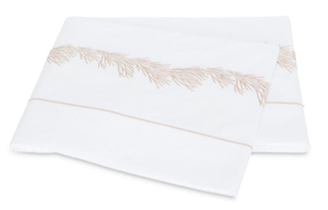 Two folded white pillowcases from the Matouk Atoll Bedding Collection, crafted from luxurious CEYLON cotton percale with a 520 thread count and adorned with a delicate beige botanical branch embroidery along the edge.