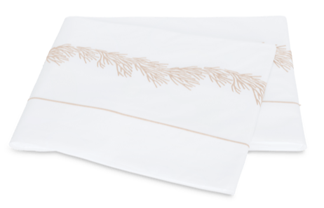 Two folded white pillowcases from the Matouk Atoll Bedding Collection, Dune, crafted from 520-thread count Ceylon cotton percale, feature an elegant beige embroidered edge pattern and are displayed on a plain background.