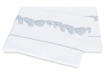 Two folded white towels from the Matouk Atoll Bedding Collection, expertly crafted from CEYLON cotton percale with a luxurious 520 thread count, showcase a delicate blue branch-like embroidered pattern and a fine blue border near the edge, all elegantly arranged on a plain background.