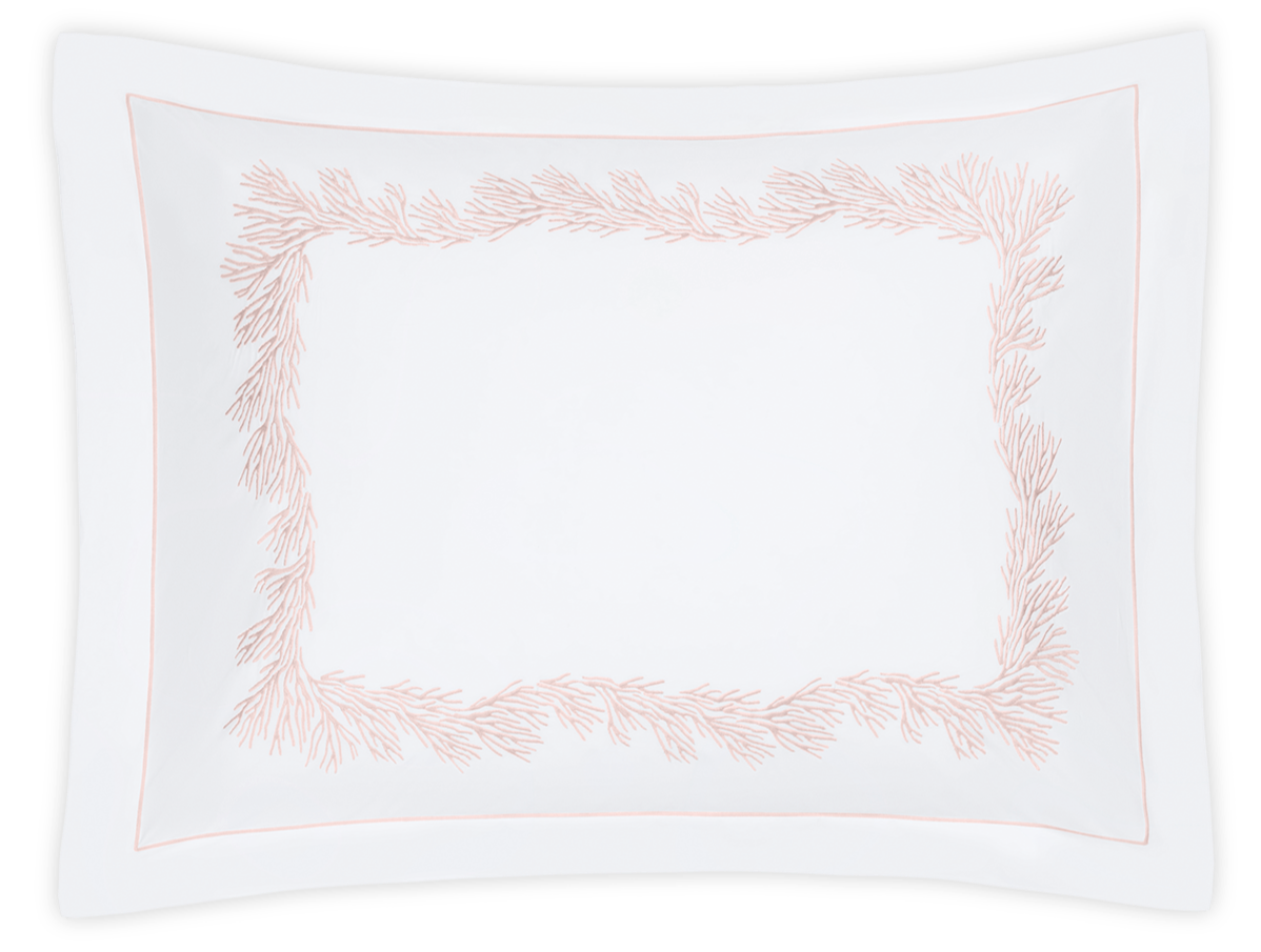 The Atoll Bedding Collection pillowcase by Matouk features blush Ceylon cotton percale and a feathery coral embroidery forming a delicate rectangular border.