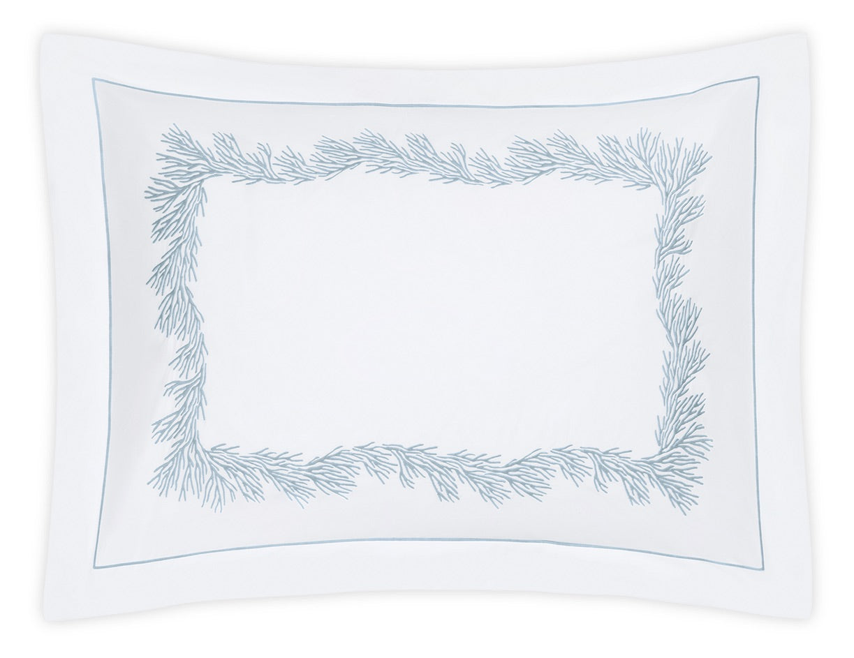 White rectangular pillowcase from the Matouk Atoll Bedding Collection, crafted from luxurious 520 thread count CEYLON cotton percale, featuring a border of light blue embroidered branch-like patterns around the edges.