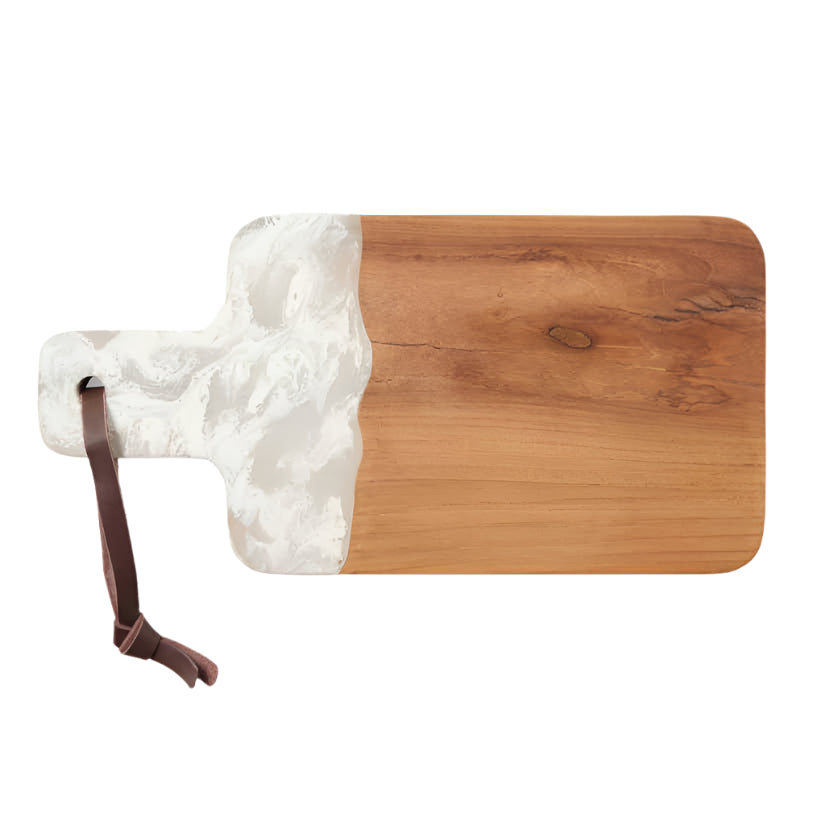 The Austin Swirled Serveware Collection by Blue Pheasant features a handcrafted rectangular teak serving board with a handle, partially covered in white resin and finished with a brown leather strap looped through the handle.