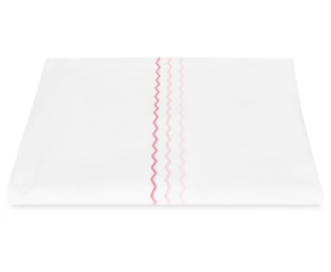The Axel Bedding Collection, Pink by Matouk features a folded white hospital blanket crafted from long-staple cotton with three parallel pink zigzag stripes—an inviting addition to any modern bed.