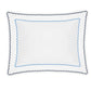 The Axel Bedding Collection by Matouk features a white rectangular pillow adorned with blue and navy scalloped trim along the edges, meticulously crafted from soft long-staple cotton and finished with subtle zigzag embroidery. Displayed on a white background, this pillow serves as the perfect accent for any modern bed.