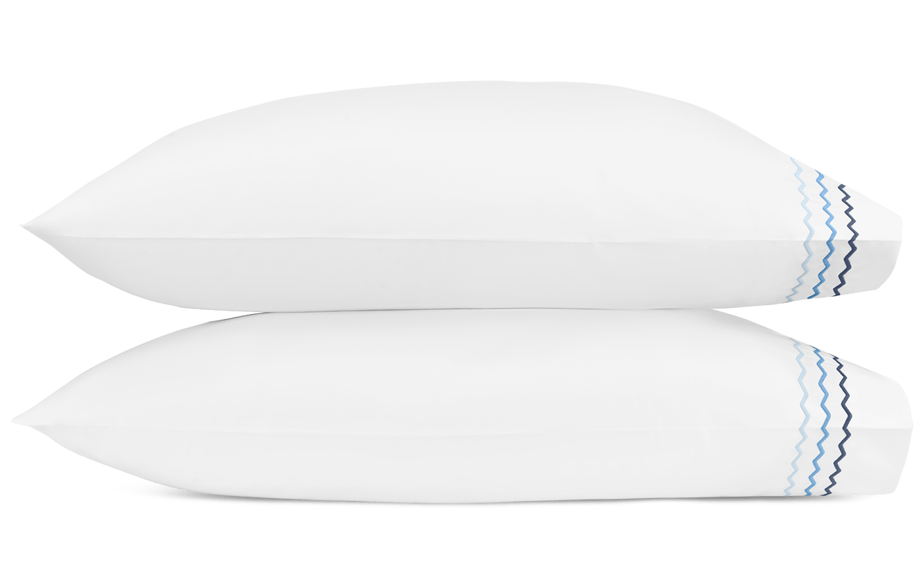 Two white pillows from the Matouk Axel Bedding Collection in Azure, made of long-staple cotton and featuring a blue wavy line pattern, add a fresh accent to any modern bed.