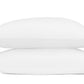 Two white pillows from the Axel Bedding Collection by Matouk are stacked on top of each other, each crafted from long-staple cotton and accented with a pink wavy stitched line near one edge, set against a plain white background.