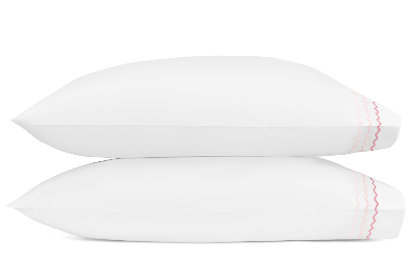 Two pink pillows from the Axel Bedding Collection by Matouk are stacked, each with delicate zigzag embroidery along the hem—an elegant accent for any modern bed. Made from soft long-staple cotton for lasting comfort.