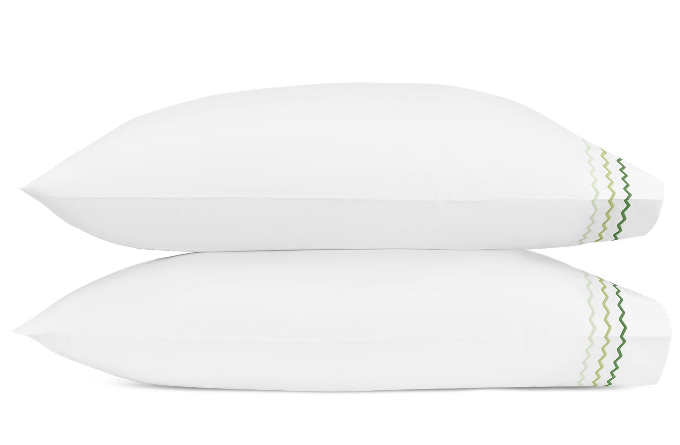 Two white pillows from the Axel Bedding Collection by Matouk are stacked together, each made from luxurious long-staple cotton and accented with a green zigzag embroidery along one edge on the right side—perfect for elevating the look of any modern bed.