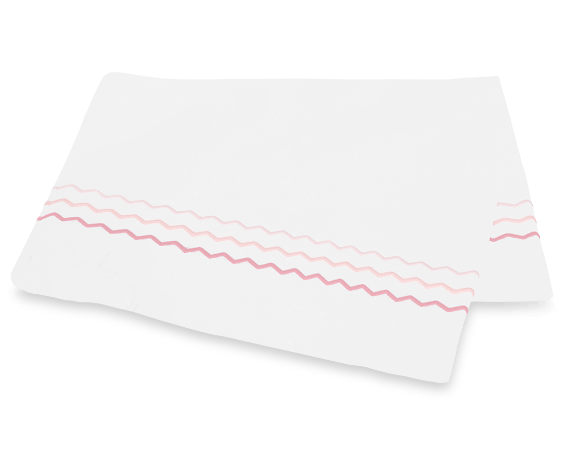 A white paper napkin featuring pink and mauve wavy lines, inspired by the Axel Bedding Collection in Pink from Matouk, rests on a white surface.