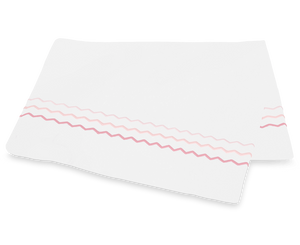 A white paper napkin featuring pink and mauve wavy lines, inspired by the Axel Bedding Collection in Pink from Matouk, rests on a white surface.