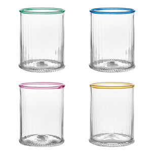 The Juliska Nell Collection features four mouth-blown clear glass tumblers with green, blue, pink, and yellow rims arranged in a 2x2 grid on a white background, showcasing Czech craftsmanship.