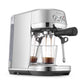 The Breville Bambino Plus Espresso Machine, made of stainless steel with a ThermoJet heating system, brews specialty coffee into two clear glass cups and features an automatic steam wand on the right side.