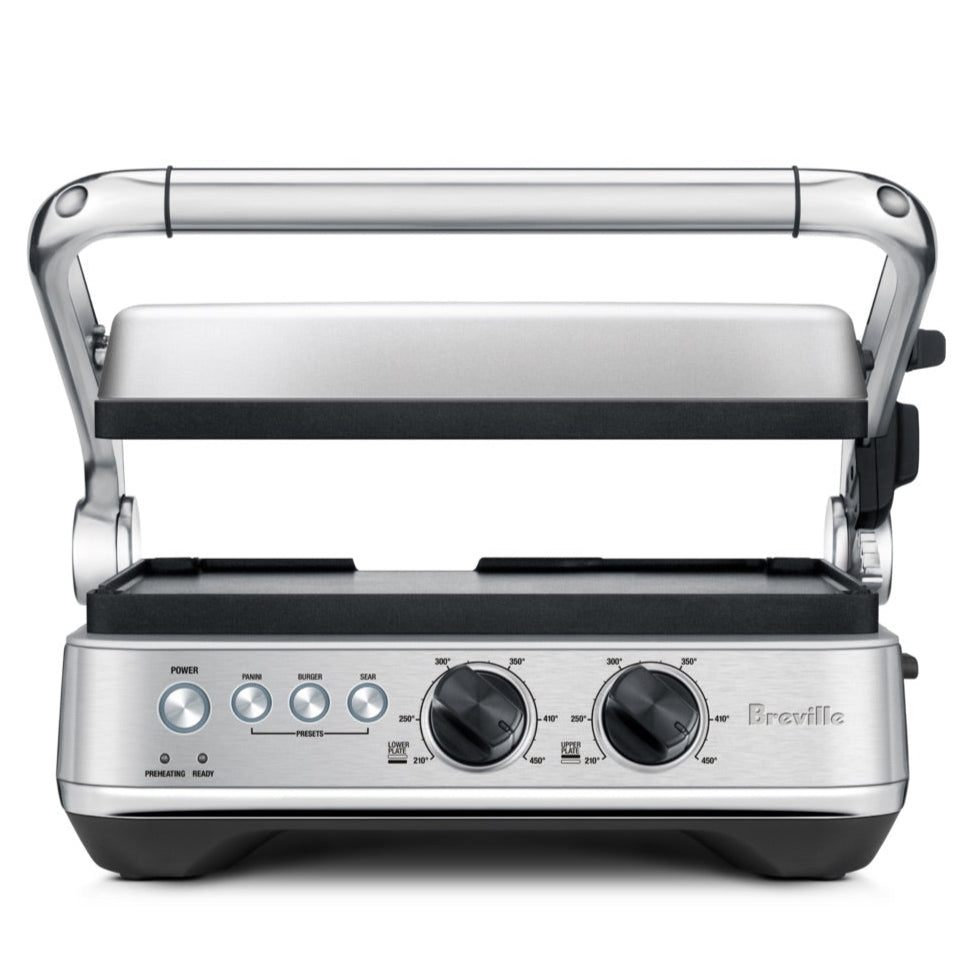 The Breville Sear & Press Grill is a stainless steel countertop grill with adjustable top lid, front control dials, and buttons, serving as a versatile panini press for delicious sandwiches and grilled foods.