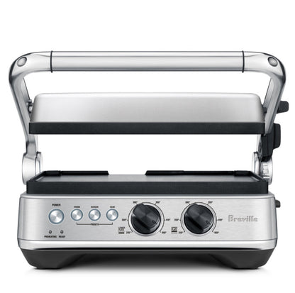 The Breville Sear & Press Grill is a stainless steel countertop grill with adjustable top lid, front control dials, and buttons, serving as a versatile panini press for delicious sandwiches and grilled foods.