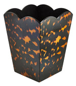The Scalloped Lacquer Waste Bin Collection by Addison Ross features a hexagonal, scalloped design with a brown and amber tortoiseshell pattern, inspired by the brand's signature style.