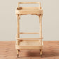 The Flore Bistro Bar Cart by Selamat, a two-tier handwoven Manau rattan cart with wheels, is shown on a terracotta tile floor against a plain beige background.