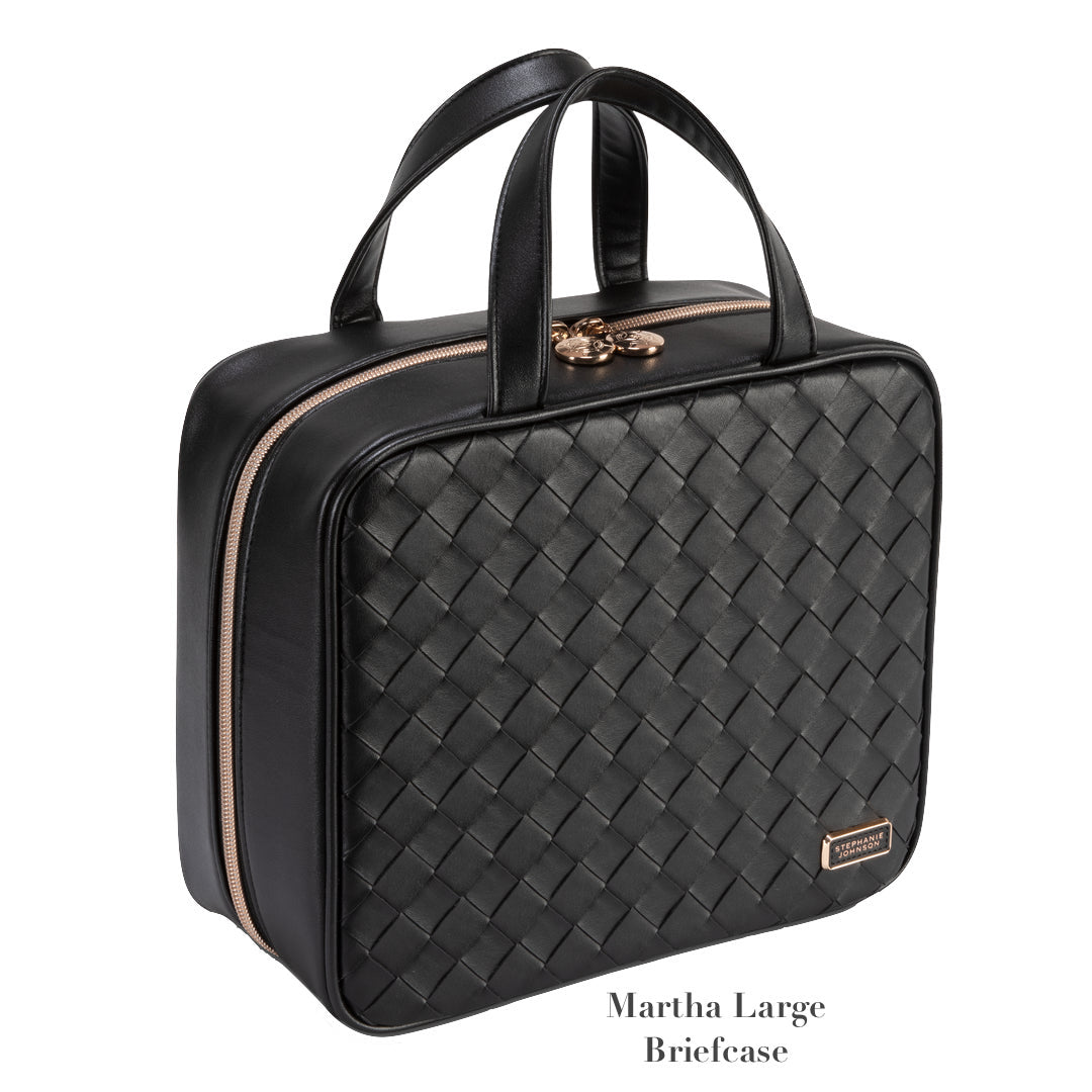 The Belize Raven Travel Collection by Stephanie Johnson is a black woven leather briefcase with double handles, gold-tone zipper, removable compartments, and a small branded tag.