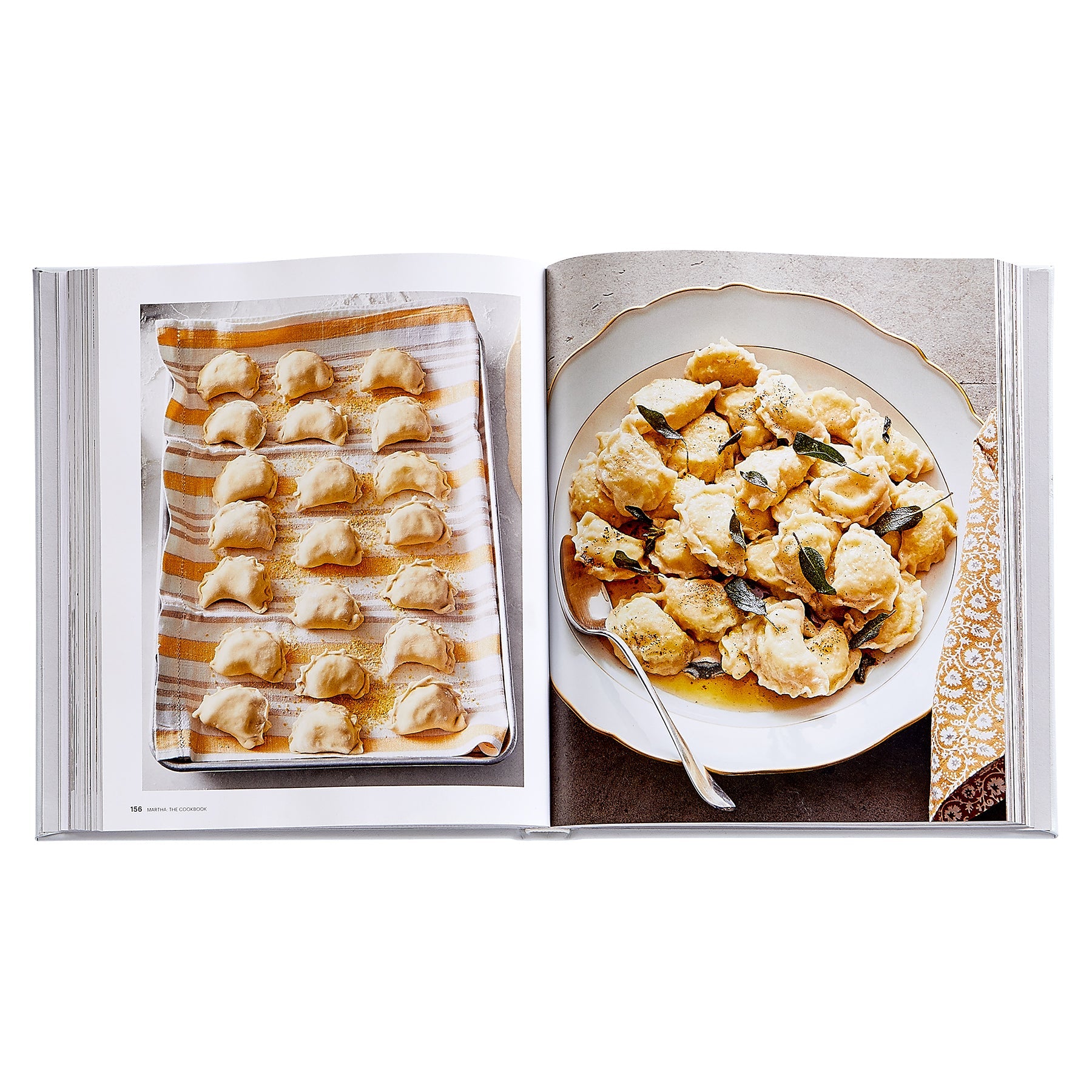 The Martha: The Cookbook, Leather Bound by Graphic Image is open to two pages—one featuring uncooked stuffed pasta on a tray, the other showing cooked pasta with sauce and herbs on a plated dish next to a fork.
