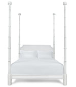The Keller Bed by Bunny Williams features tall, sculpted four posts, a rectangular headboard, and white bedding, beautifully photographed against a plain white background.