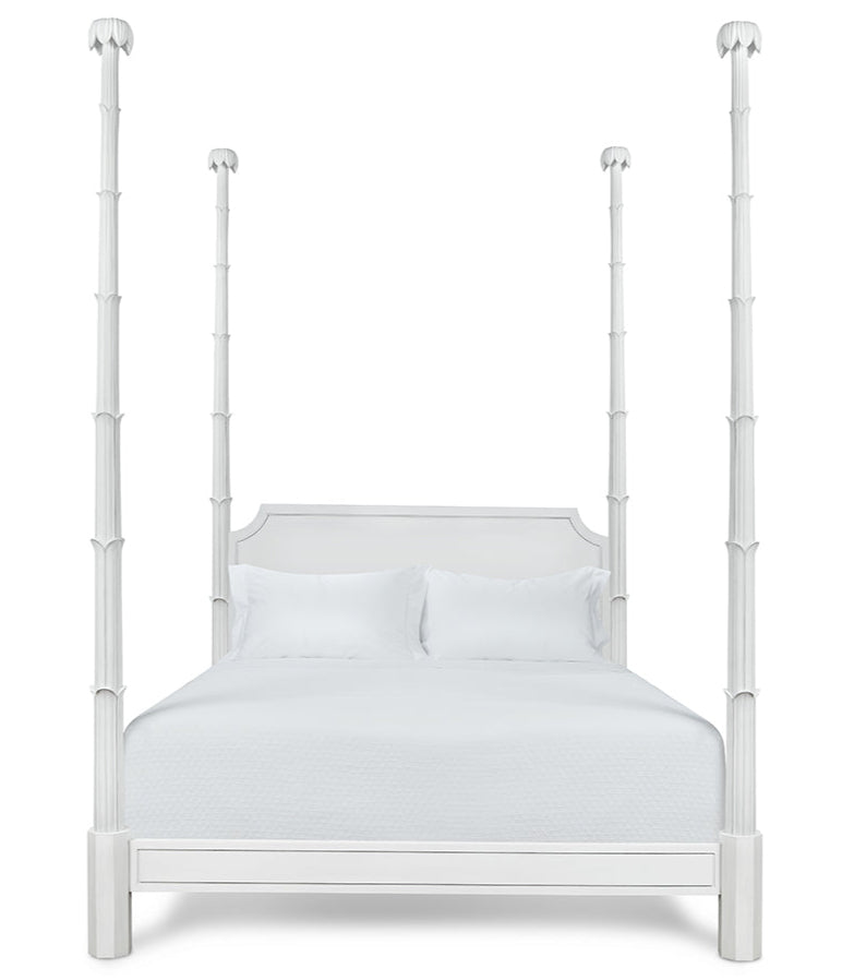 The Keller Bed by Bunny Williams features tall, sculpted four posts, a rectangular headboard, and white bedding, beautifully photographed against a plain white background.