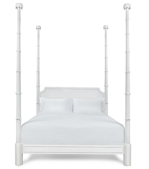 The Keller Bed by Bunny Williams features tall, sculpted four posts, a rectangular headboard, and white bedding, beautifully photographed against a plain white background.