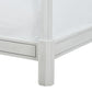 Close-up of the Keller Bed by Bunny Williams, featuring a carved, white-painted frame corner and a textured white bedspread.
