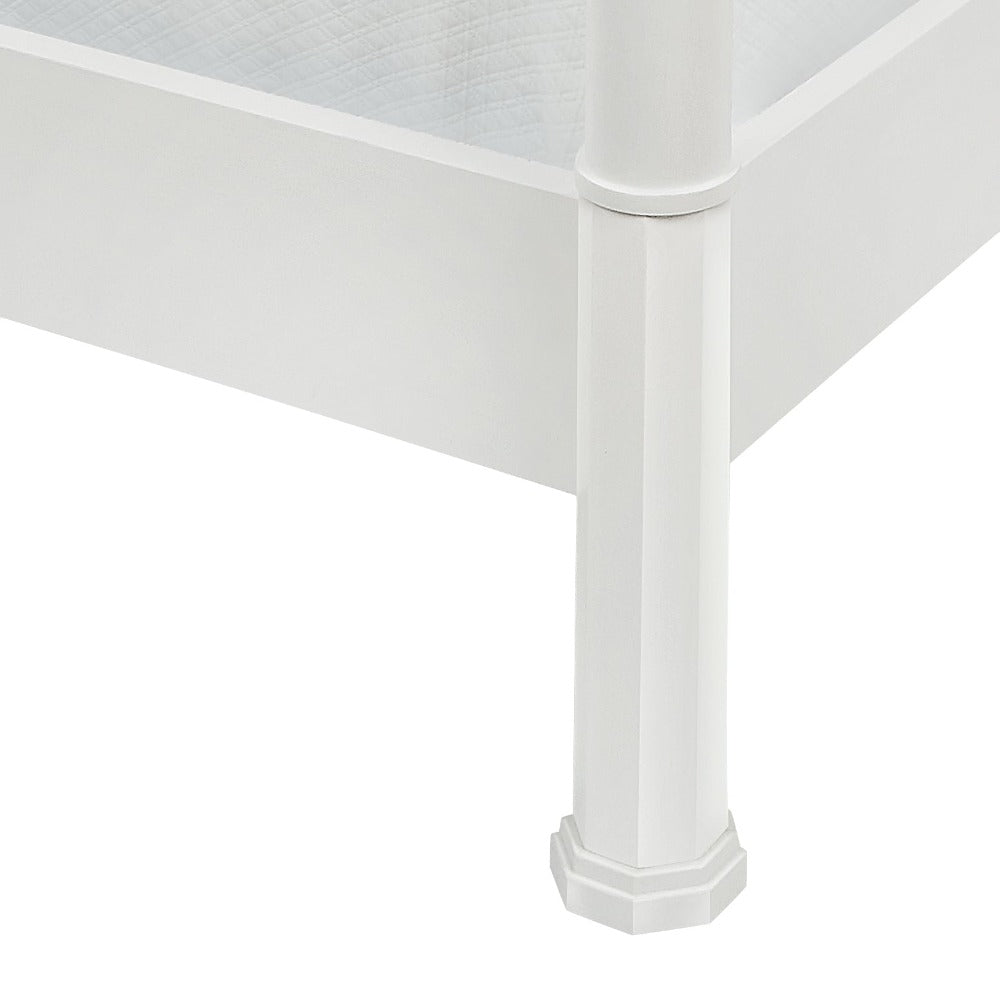 Close-up of the corner of the Garbo King Bed by Bunny Williams, featuring a traditional white wooden frame with a hexagonal bedpost, side rails, and a quilted mattress inside.