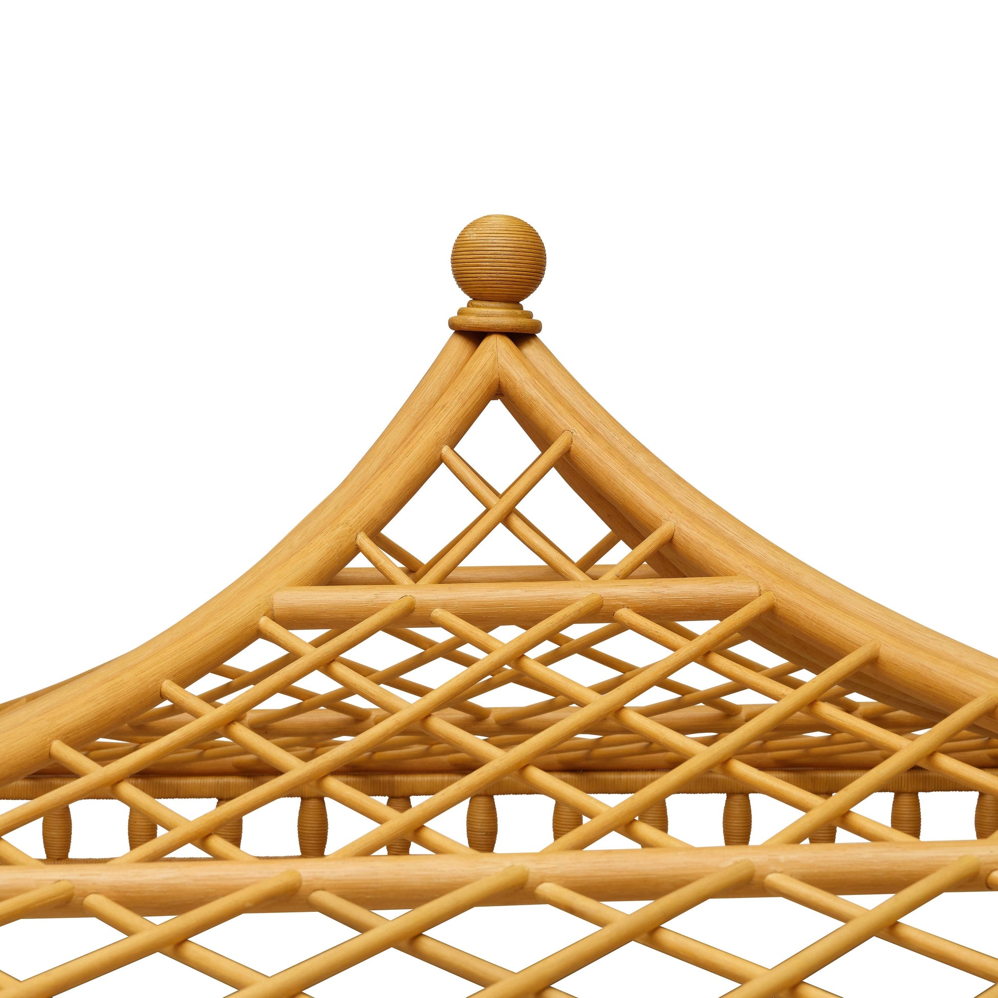 Close-up of a decorative wooden structure with an elegant lattice design and pointed top, echoing the Bunny Williams Rattan Trellis Canopy Bed, shown against a white background.