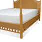 A close-up of the Bunny Williams Rattan Trellis Canopy Bed showcases its wooden frame with woven wicker and white mattress, highlighting the subtle lattice design.