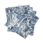 A set of four Balthazar Napkins by Matouk, featuring a striking blue and white marbled pattern, are stacked unevenly against a white background—bringing an elegant and sophisticated touch to your table setting for any occasion.