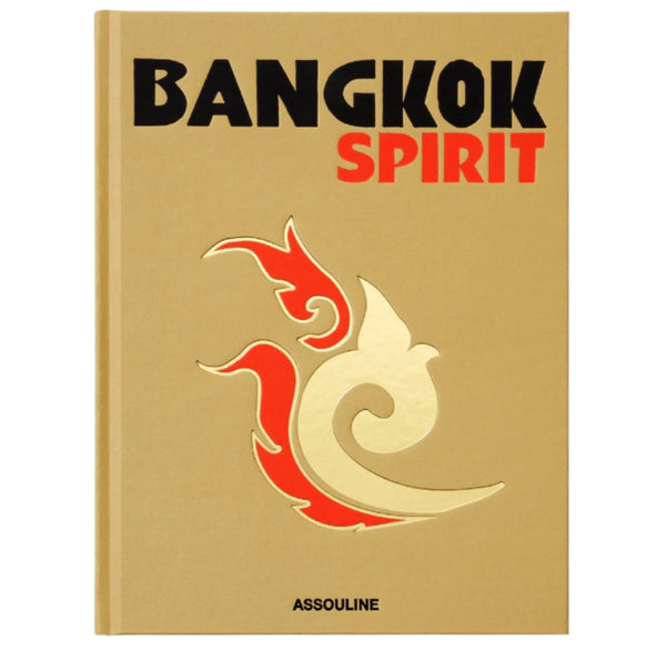 The cover of Assouline's "Bangkok Spirit" features a gold backdrop with an abstract design in red and gold, reflecting the vibrant street-food scene and serene Buddhist temple elegance of Bangkok.