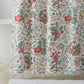 A white shower curtain from the Matouk Pomegranate Shower Curtain Collection, featuring a vibrant botanical floral pattern inspired by Schumacher designs, hangs in front of a white bathtub; a coordinating white towel and bath mat complete the look.
