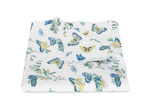 The Baudin Butterfly Blue Bedding Collection by Matouk features a folded percale blanket in white Egyptian cotton with blue and yellow butterfly and botanical floral prints.