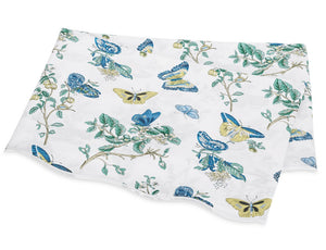 The Matouk Baudin Butterfly Blue Bedding Collection features folded white Egyptian cotton percale with botanical motifs, including blue, yellow, and green butterfly prints and leafy branches.