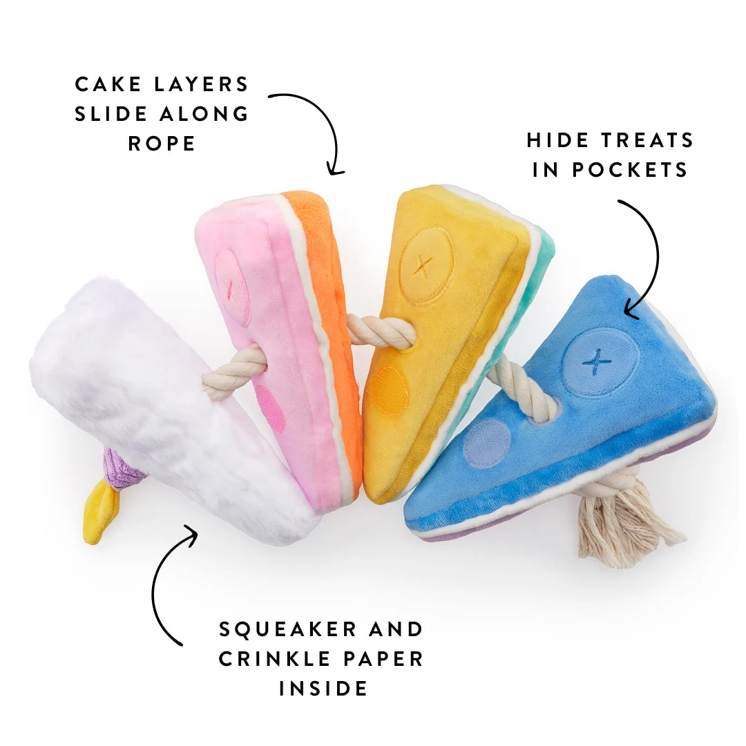 The Birthday Cake Interactive Snuffle Dog Toy by The Foggy Dog features three vibrant plush cake slices connected by a tug-friendly rope, with squeakers, crinkle paper, treat pockets, and movable layers—making it a fun and engaging interactive toy for hours of play.